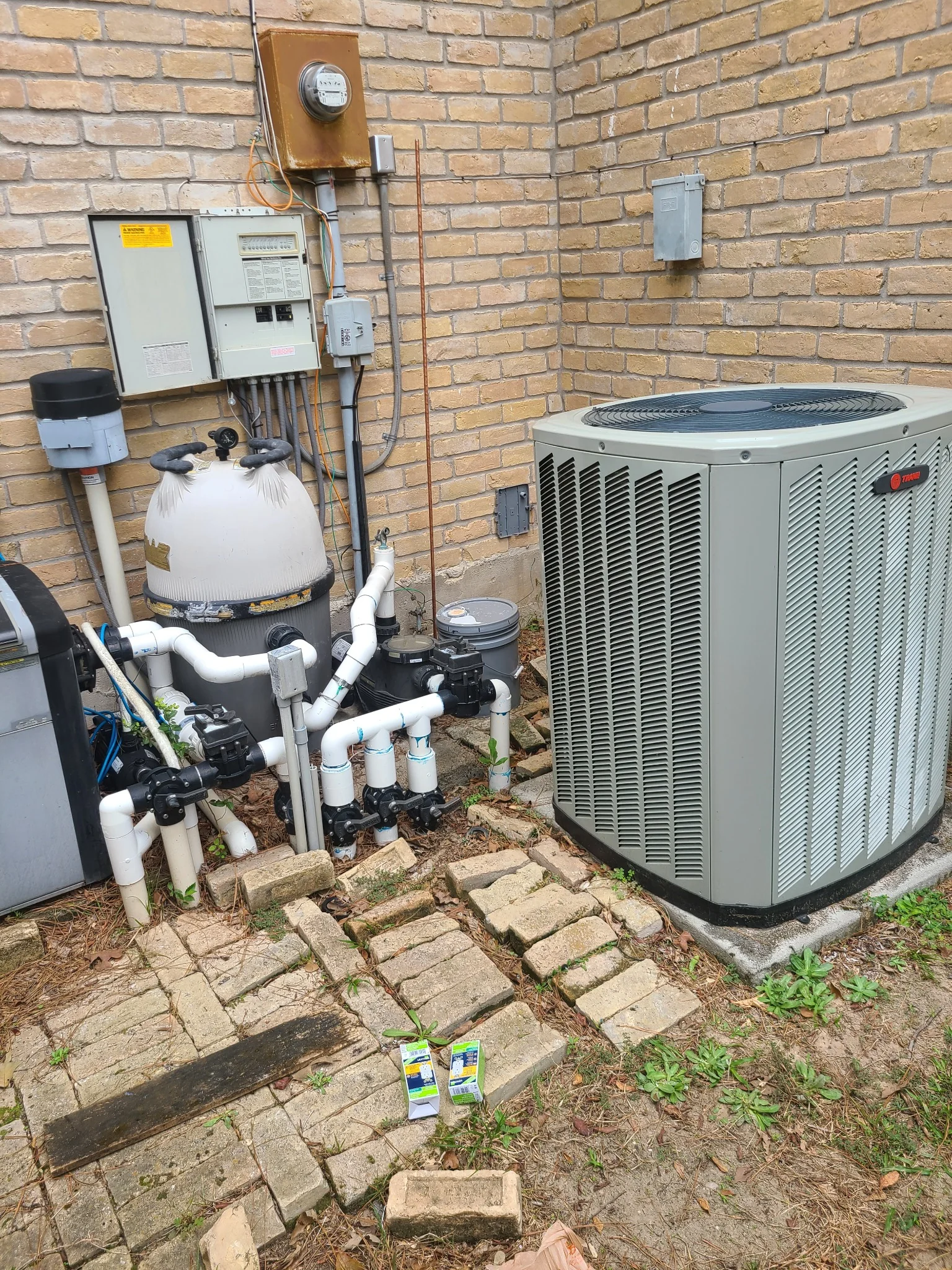 Trane residential condenser installed near outdoor pool equipment